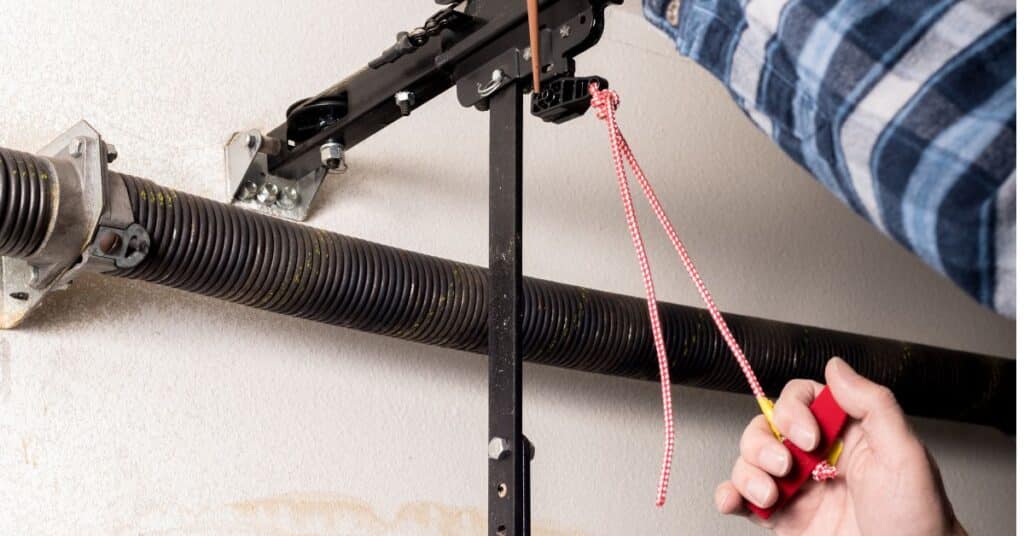 A person pulls a red rope hanging from a garage door mechanism